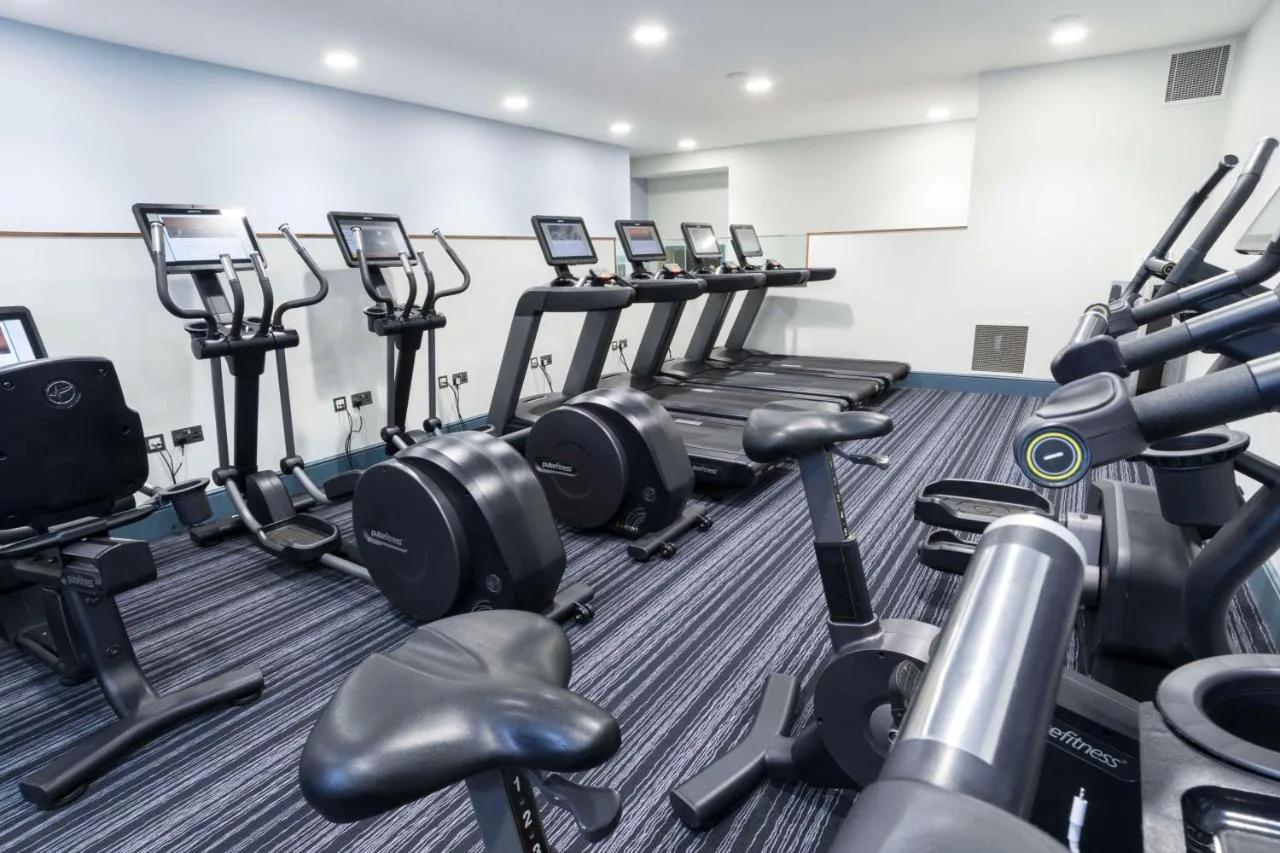 a gym with rows of treadmills and machines at The Midland in Manchester